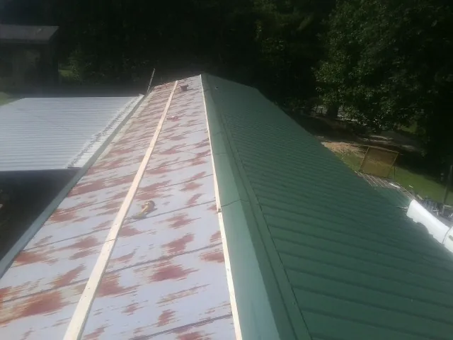 Old rusted panels beside newly installed green metal roofing — Wind Damage Roof Repair by Roofing Brothers in Smithville