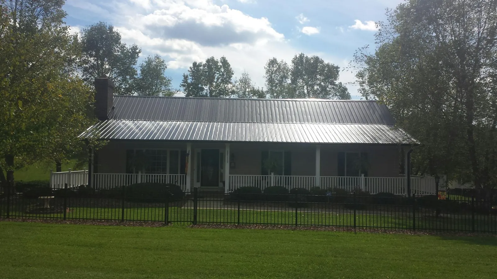 Gray metal roof on a brick ranch with a full width front porch — Gutter Guard Installation work by our crew in Smithville