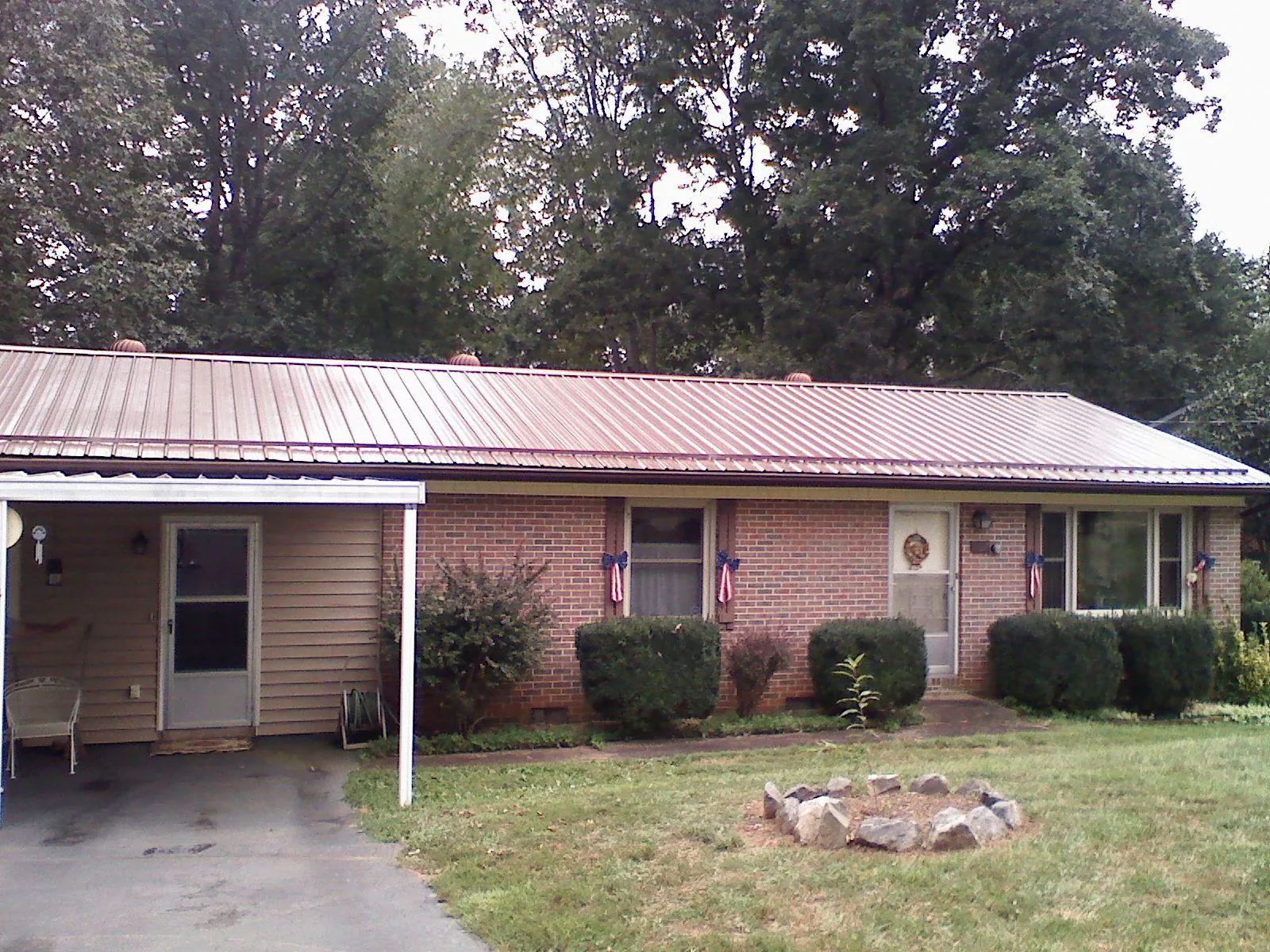 Bronze metal roof and carport on a brick ranch home — Roof Repair work by our crew in Smithville